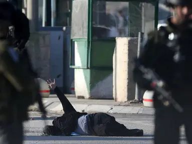 Seorang wanita Palestina terlihat kesakitan usai tertembak oleh polisi Israel di Qalandiya pos pemeriksaan dekat kota Ramallah, Tepi Barat (30/12). Menurut keterangan petugas, wanita tersebut mencoba menusuk salah satu polisi. (Reuters/Mohamad Torokman)