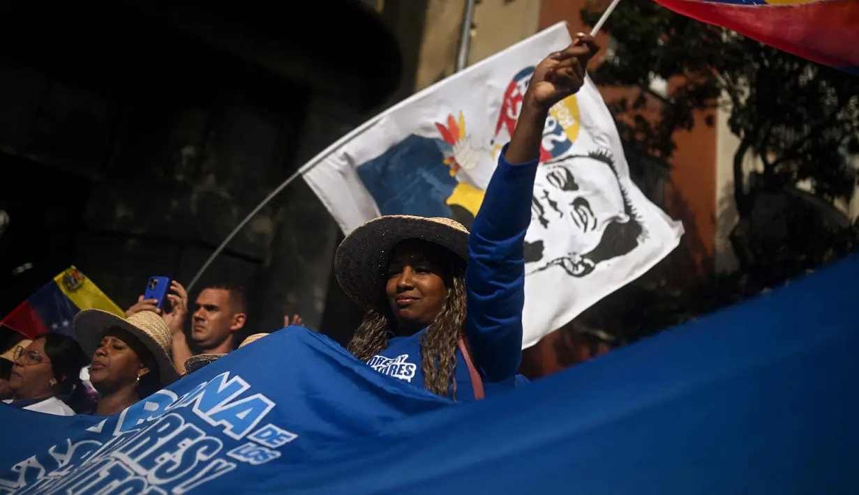 Masa berkabung nasional ini untuk menghormati korban yang tewas dalam serangan militer Amerika Serikat yang menggulingkan Presiden Nicolas Maduro. Tampak dalam foto, seorang wanita mengibarkan bendera Venezuela selama unjuk rasa dukungan untuk mantan Presiden Venezuela Nicolas Maduro dan istrinya Cilia Flores di Caracas pada 6 Januari 2026. (Federico PARRA/AFP)