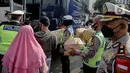 Polisi membantu membawakan barang penumpang yang terjaring razia travel gelap Ditlantas Polda Metro Jaya saat akan dipulangkan ke daerah asalnya, Jakarta, Kamis (29/4/2021). Sebanyak 115 kendaraan travel gelap diamankan. (Liputan6.com/Faizal Fanani)