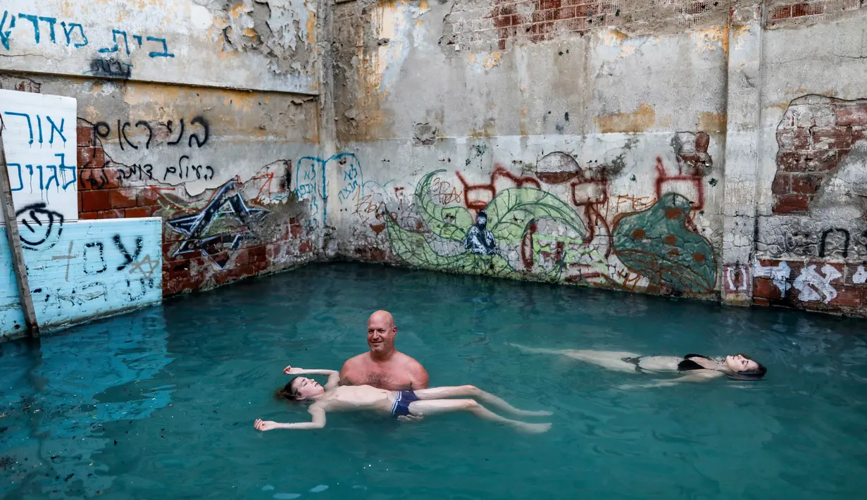 Wisatawan berenang di kolam air panas di ujung selatan Dataran Tinggi Golan yang dianeksasi Israel, dekat perbatasan dengan Yordania, 1 Maret 2019. Kolam dengan air panas itu berasal dari aliran pipa pengeboran di Lembah Hula. (MENAHEM KAHANA/AFP)