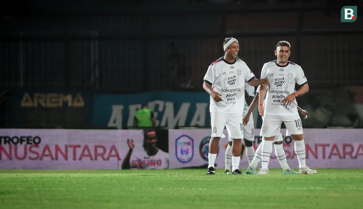 Bersama Rans Nusantara FC, mantan pemain Barcelona, Ronaldinho (kiri) melakukan duet dengan Cristian Gonzales dalam pertandingan pertama Trofeo Ronaldinho melawan Persik Kediri. (Bola.com/Iwan Setiawan)