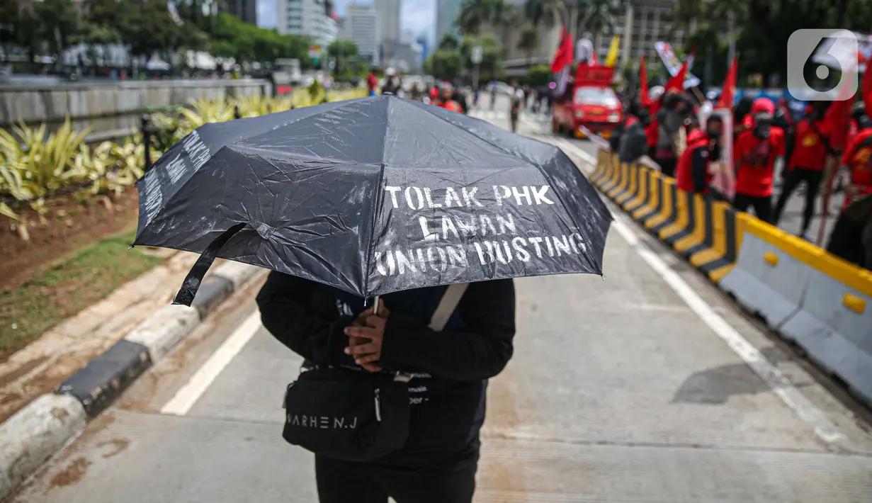 Massa mengenakan payung saat berunjuk rasa di kawasan Patung Kuda, Jakarta, Kamis (22/10/2020). Dalam aksi yang digelar bertepatan dengan setahun pemerintahan Presiden Joko Widodo-Wapres Ma'ruf Amin itu massa meminta dikeluarkannya Perppu pencabutan UU Cipta Kerja. (Liputan6.com/Faizal Fanani)