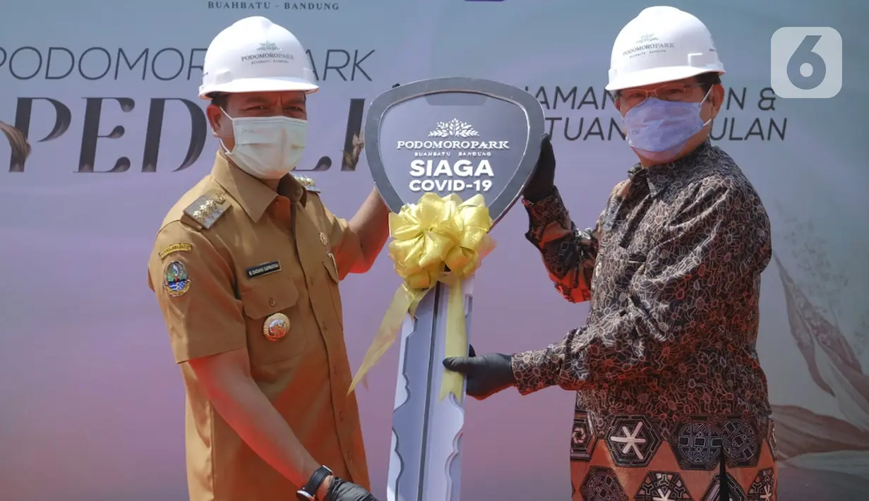 Direktur Utama Pesona Mitra Kembar Mas Adhi Romzy (kanan) secara simbolis menyerahkan mobil ambulans siaga Covid-19 kepada Bupati Kabupaten Bandung Dadang Supriatna di Bandung, Selasa (10/08/2021). (Liputan6.com/Pool/Podomoro Park)