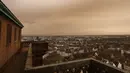 Pemandangan kota Strasbourg tampak diselimuti debu Sahara berwarna oranye bergerak di atas kota di Prancis timur (15/3/2022). Badai di gurun Sahara menciptakan badai besar hembusan angin, yang mengangkat pasir ke udara. (AP Photo/Jean-Francois Badias)