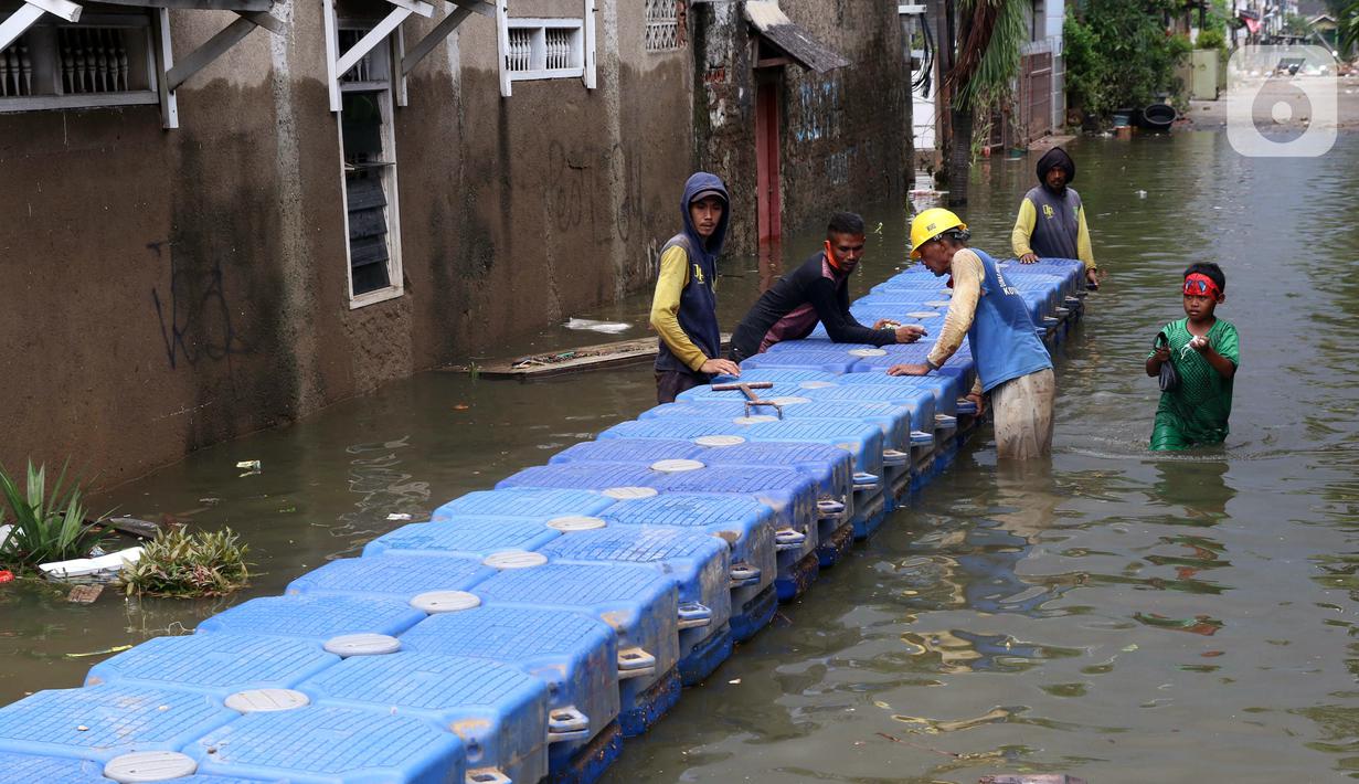 Petugas membuat jembatan apung saat banjir melanda Perumahan Periuk Damai, Tangerang, Banten, Selasa (23/2/2021). Adanya jembatan apung mempermudah warga saat melintasi banjir setinggi 2,5 meter di tempat tersebut. (Liputan6.com/Angga Yuniar)
