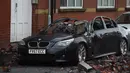 Reruntuhan atap apartemen tampak menimpa sebuah mobil yang diparkir akibat angin kencang yang melanda di Leigh, barat laut Inggris, Rabu (18/11). (AFP PHOTO/Paul Ellis)
