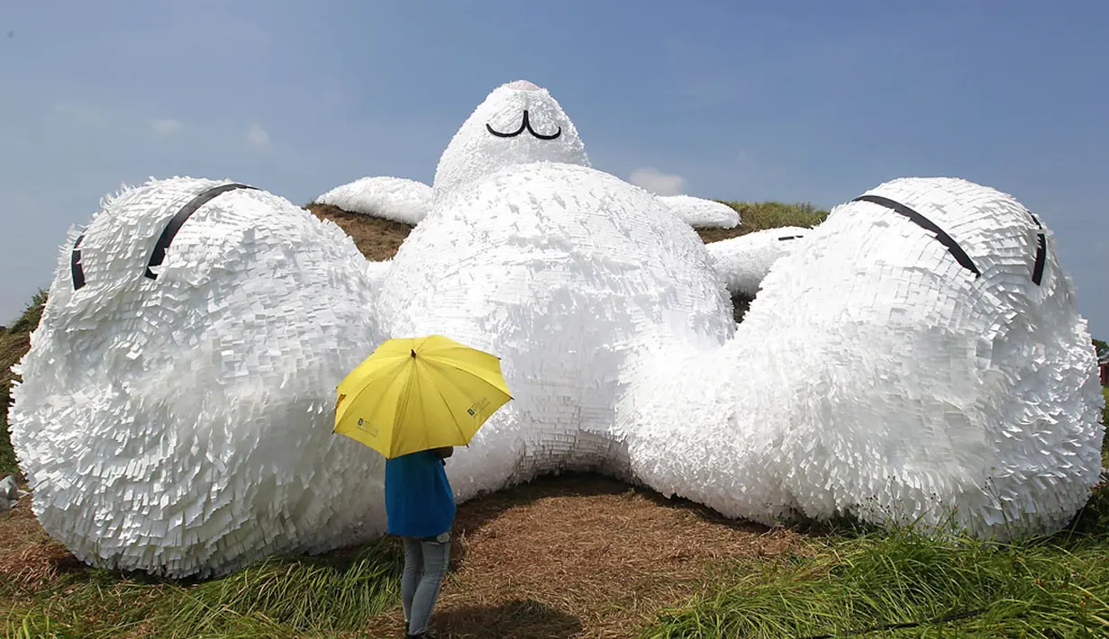 Salah satu pengunjung berdiri di depan kelinci raksasa yang dirancang oleh seniman Belanda Florentijn Hofman dan dipamerkan pada Taoyuan Land Art Festival di Taiwan, (3/9/2014). (REUTERS/Pichi Chuang)