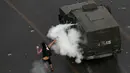 Demonstran melemparkan gas air mata ke arah kendaraan polisi di Santiago, Chile (4/10/2019). Pengunjuk rasa menuntut diakhirinya ketidaksetaraan ekonomi bahkan ketika pemerintah mengumumkan bahwa demonstrasi selama berminggu-minggu merugikan pertumbuhan ekonomi negara. (AP Photo/Esteban Felix)