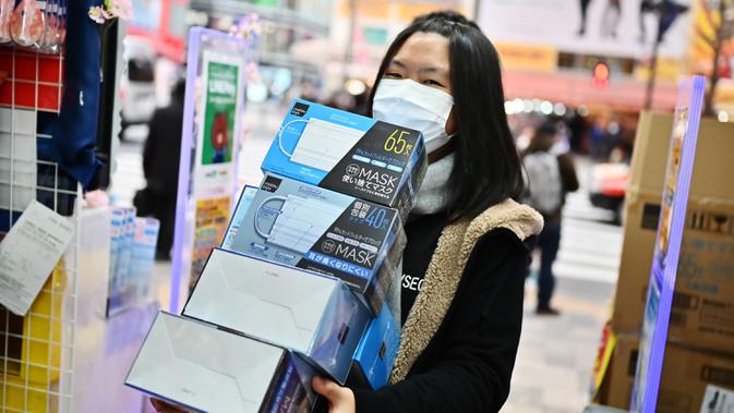 Seorang wanita membeli masker dari apotek di daerah Akihabara Tokyo (27/1/2020). Merebaknya virus corona yang mematikan membuat warga Tokyo berburu masker. (AFP Photo/Charly Triballeau)