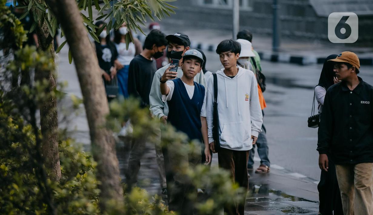 Seorang remaja berselfie di Taman Sudirman, Jakarta, Rabu (6/7/2022). Tempat ini viral karena jadi ajang adu fashion anak Citayam, Bekasi hingga Bojong Gede. Mereka mengenakan kemeja flanel oversize, celana model 90-an seperti boot cut atau cutbray, sneakers klasik, dan tentu saja topi. (Liputan6.com/Faizal Fanani)
