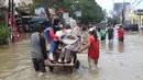 Warga melintasi banjir dengan menaiki ojek gerobak di Ciledug, Tangerang, Banten, Kamis (2/1/2020). Jasa ojek gerobak menjadi alternatif bagi warga untuk melintasi banjir. (Liputan6.com/Angga Yuniar)
