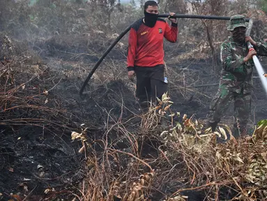 Prajurit TNI dan petugas Badan Penanggulangan Bencana Daerah (BPBD) berusaha memadamkan kebakaran hutan dan lahan di Kabupaten Kampar, Provinsi Riau (12/9/2019). Titik api kebakaran yang terjadi di Indonesia telah melonjak tajam. (AFP Photo/Adek Berry)