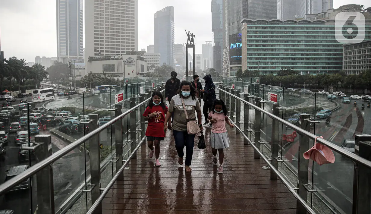 Warga berjalan di JPO Bundaran HI, Jakarta, Rabu (28/12/2022). Walau sempat disebutkan ada potensi badai dahsyat yang melanda kawasan Jakarta–Bogor–Depok–Tangerang–Bekasi (Jabodetabek) pada hari ini, warga Jakarta terpantau masih banyak beraktivitas di luar ruangan. (Liputan6.com/Faizal Fanani)
