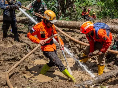 Petugas penyelamat menggunakan selang bertekanan tinggi untuk menyemprotkan air selama operasi penyelamatan di lokasi longsor Desa Situkung, Banjarnegara, Jawa Tengah, pada Rabu 19 November 2025. Hari keempat operasi pencarian korban tanah longsor di Dusun Situkung, Desa Pandanarum, Kabupaten Banjarnegara, Jawa Tengah, atau Rabu 19 November 2025, tim pencari dan penyelamat gabungan berhasil menemukan satu korban meninggal. (DEVI RAHMAN/AFP)