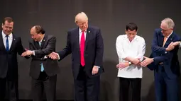 Presiden AS, Donald Trump menengok ke kanan dan ke kiri saat kebingungan melakukan salaman khas ASEAN pada upacara pembukaan KTT ASEAN di Manila, Filipina, Senin (13/11). Trump tampak kesulitan menempatkan tangannya. (AP/Andrew Harnik)