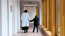 Seorang dokter yang sedang membimbing salah satu anak berjalan di lorong Rumah Sakit Ecole di Neuilly-Plaisance, dekat Paris, 21 Maret 2017. Rumah sakit yang khusus untuk anak penderita autis ini baru saja dibuka untuk umum. (BERTRAND GUAY/AFP)