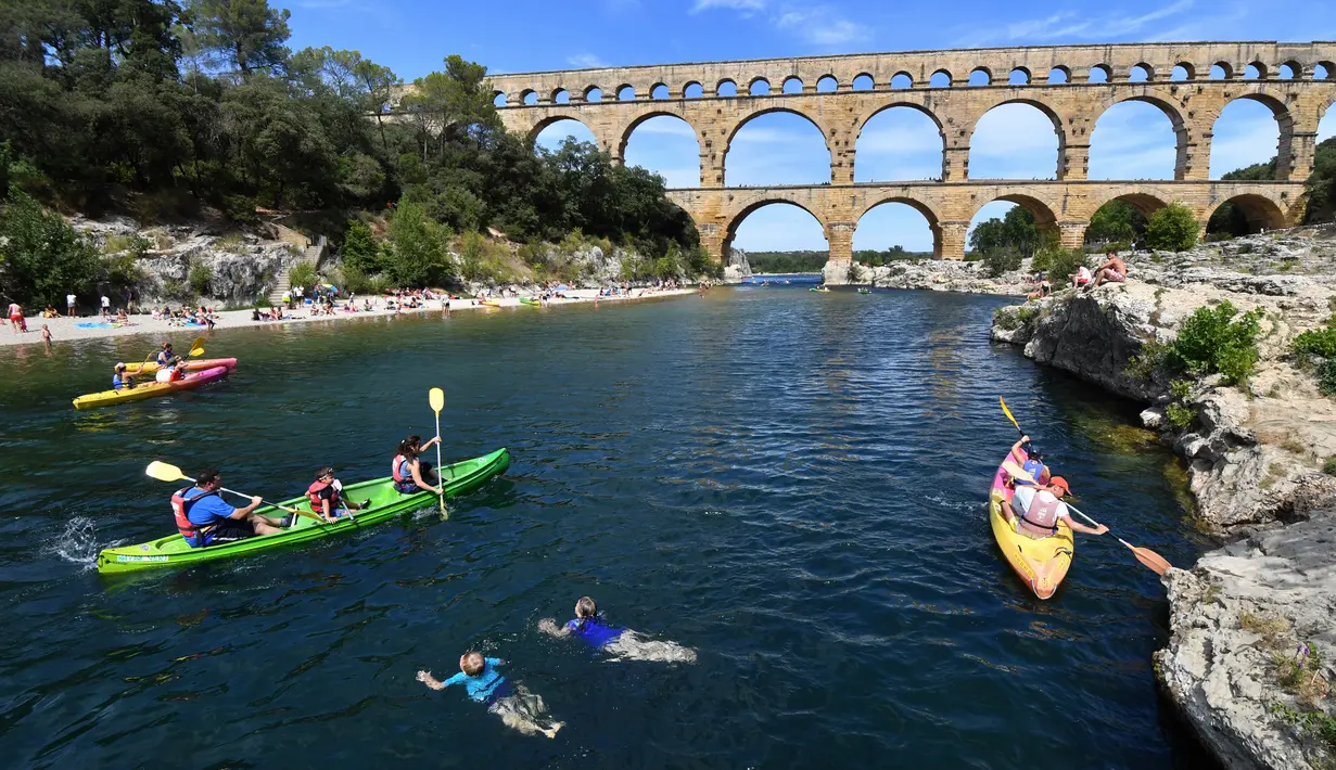 Wisatawan bermain kayak di dekat Pont du Gard atau Jembatan Gard di Vers-Pont-du-Gard, Prancis, Rabu (21/8/2019). Pont du Gard merupakan jembatan saluran air dari batu yang terdiri dari tiga tingkatan. (Pascal GUYOT/AFP)