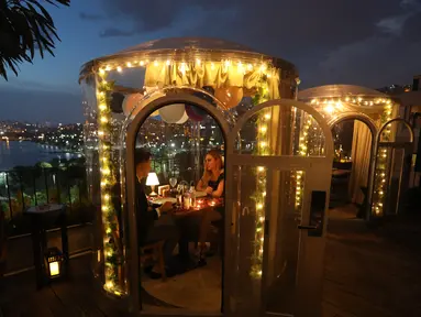 Pasangan menikmati makan malam mereka di zona aman yang disediakan sebuah restoran di Istanbul, Turki (16/6/2020). Sebuah restoran kelas atas di Sutluce, suatu kawasan di sisi Eropa Kota Istanbul, membuat pelanggannya merasa tenang di dalam zona aman. (Xinhua/Osman Orsal)