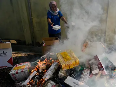 Petugas Bea dan Cukai membakar barang hasil penindakan berupa rokok impor ilegal saat pemusnahan di Banda Aceh, Aceh, Selasa (22/7/2025). (CHAIDEER MAHYUDDIN/AFP)