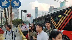 Warga menunggu angkutan umum di tepi Jalan Jenderal Sudirman, Jakarta, Senin (8/7/2019). Tidak adanya halte menyebabkan warga terpaksa menunggu angkutan umum di tempat seadanya. (Liputan6.com/Immanuel Antonius)