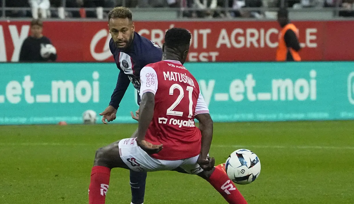 Penyerang Paris Saint-Germain (PSG) Neymar menyelipkan bola melewati gelandang Reims Azor Matusiwa dalam pertandingan pekan ke-10 Liga Prancis di Stade Auguste-Delaune II, Minggu (9/10/2022) dini hari WIB. PSG harus puas bermain imbang 0-0 melawan Stade de Reims. (AP Photo/Michel Euler)