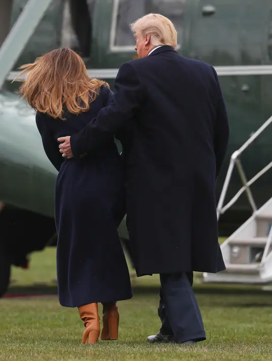 Presiden AS Donald Trump terlihat memegang Melania Trump yang hampir terjatuh saat berjalan menuju helikopter kepresidenan di halaman berumput Gedung Putih, Senin (19/3). Trump dan Melania hendak bertolak ke New Hempshire. (AP/Pablo Martinez Monsivais)