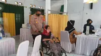 Kapolsek Sukmajaya, AKP Syafri Wasdar saat mendampingi lansia mengikuti vaksinasi yang di gelar Polsek Sukmajaya. (Liputan6.com, Dicky Agung Prihanto)