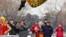 Seorang perenang musim dingin berkostum badut melompat ke dalam danau yang sebagian membeku di Shenyang, provinsi Liaoning, China, Selasa (19/2). Mereka percaya berendam di sungai dengan suhu yang ekstrem baik untuk kesehatan. (Photo by STR / AFP)