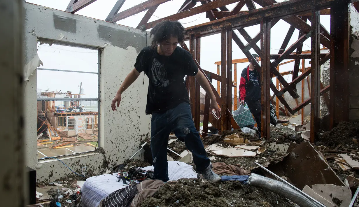 Dua orang pria mengumpulkan barang-barang yang masih tersisa dirumah mereka usai dilanda badai Harvey di Rockport, Texas (26/8). (Courtney Sacco/Corpus Christi Caller-Times via AP)
