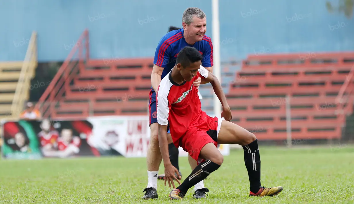 Legenda Manchester United, Denis Irwin (kanan) membantu pemain yang terjatuh pada acara United Way Coaching Clinic You C 1000 di Stadion Soemantri Brojonegoro, Jakarta, Sabtu (7/5/2016). (Bola.com/Nicklas Hanoatubun)