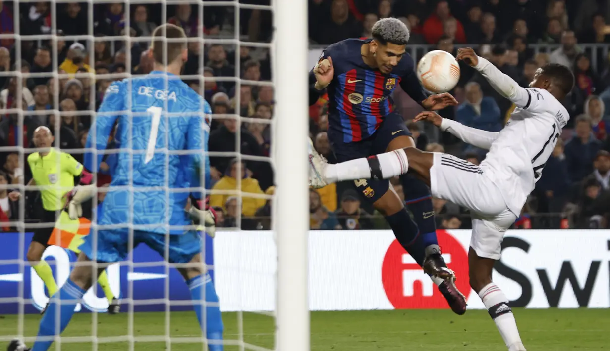 Bek Barcelona Ronald Araujo menyundul bola melewati bek Manchester United (MU) Tyrell Malacia pada leg pertama play-off babak gugur Liga Europa 2022/2023 di Camp Nou, Jumat (17/2/2023) WIB. Pertandingan antara Barcelona dan MU berakhir dengan skor sama kuat 2-2. (AP Photo/Joan Monfort)