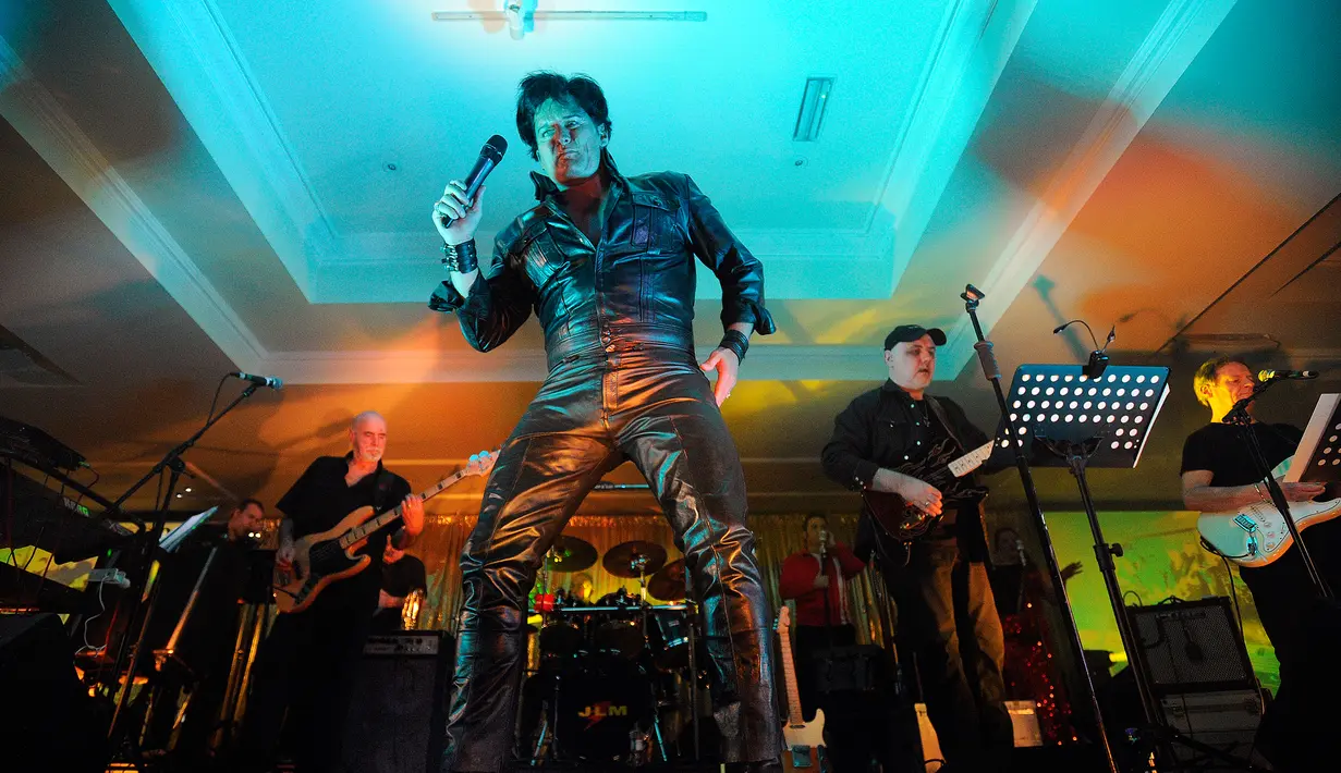 Aksi Simon Patrick saat menirukan gaya Elvis Presley pada Festival Elvis Skotlandia yang digelar pertama kali di Grangemouth, 8 April 2016. Acara ini memikat penonton yang ingin menyaksikan aksi kontestan mirip Elvis Presley. (Andy Buchanan/AFP)
