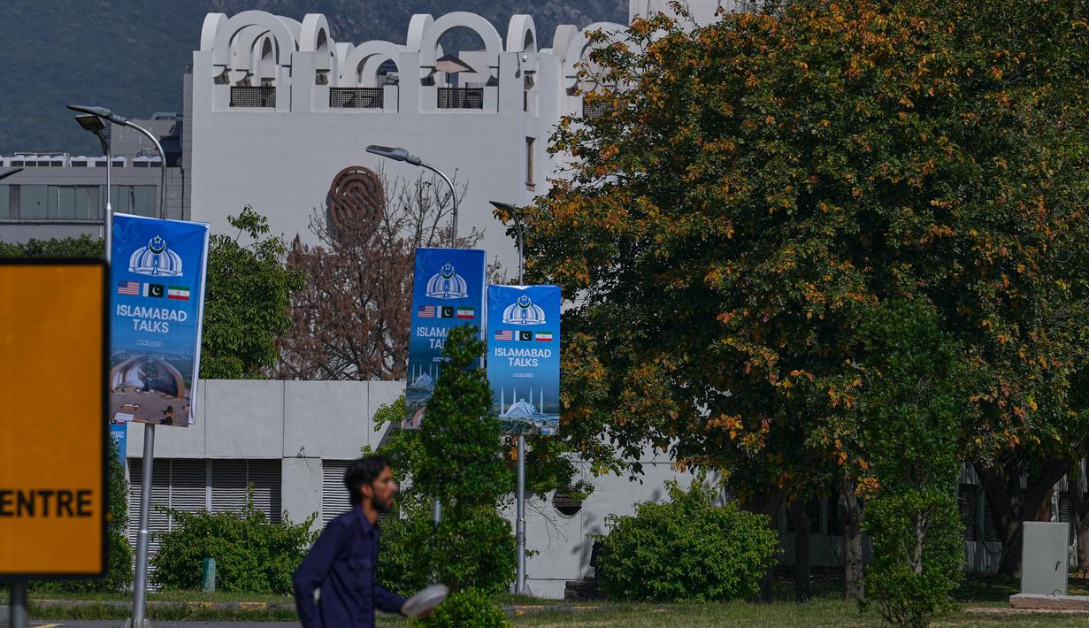 Ketika itu, Amerika Serikat dan Israel melancarkan serangan udara gabungan ke target-target strategis di Iran. Tampak dalam foto, seorang pekerja berjalan melewati papan reklame menjelang putaran kedua negosiasi antara Amerika Serikat dan Iran, di Islamabad, Pakistan, Senin 20 April 2026. (AP Photo/Anjum Naveed)
