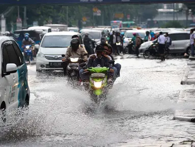 Pelajar yang mengendarai motor menerobos genangan air di kawasan Jalan Merdeka Timur, Jakarta, Selasa (1/11). Hujan deras disertai angin yang mengguyur wilayah Jakarta, mengakibatkan genangan di sejumlah ruas jalan. (Liputan6.com/Faizal Fanani)