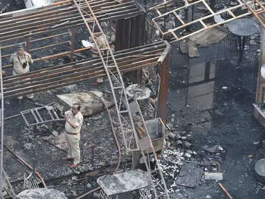 Polisi India menyelidiki sisa-sisa bangunan yang hangus terbakar di sebuah restoran di Mumbai, India (29/12). Restoran yang populer di India tersebut ludes terbakar dan mengakibatkan 15 orang tewas. (29/12 (AFP Photo/Indranil Mukhrejee)