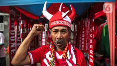 Pedagang mengenakan atribut timnas Indonesia jelang pertandingan AFF 2022 antara Indonesia melawan Thailand di Stadion Gelora Bung Karno, Jakarta, Kamis (29/12/2022). Atribut timnas Indonesia seperti kaos, syal, dan topi dijual dengan kisaran harga Rp35.000 hingga Rp75.000. (Liputan6.com/Faizal Fanani)