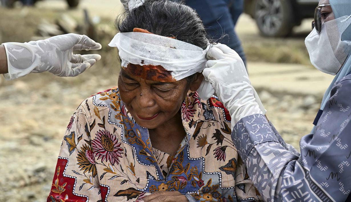 Peringatan ini didasarkan pada kondisi lingkungan pasca banjir yang kotor dan air yang tercemar, yang menjadi media ideal bagi penyebaran penyakit berbasis lingkungan. Tampak dalam foto, seorang perempuan menerima perawatan medis akibat cedera kepala di tengah kerusakan akibat banjir bandang di Aceh Tamiang, Provinsi Aceh, pada Sabtu 6 Desember 2025. (YT HARIONO/AFP)