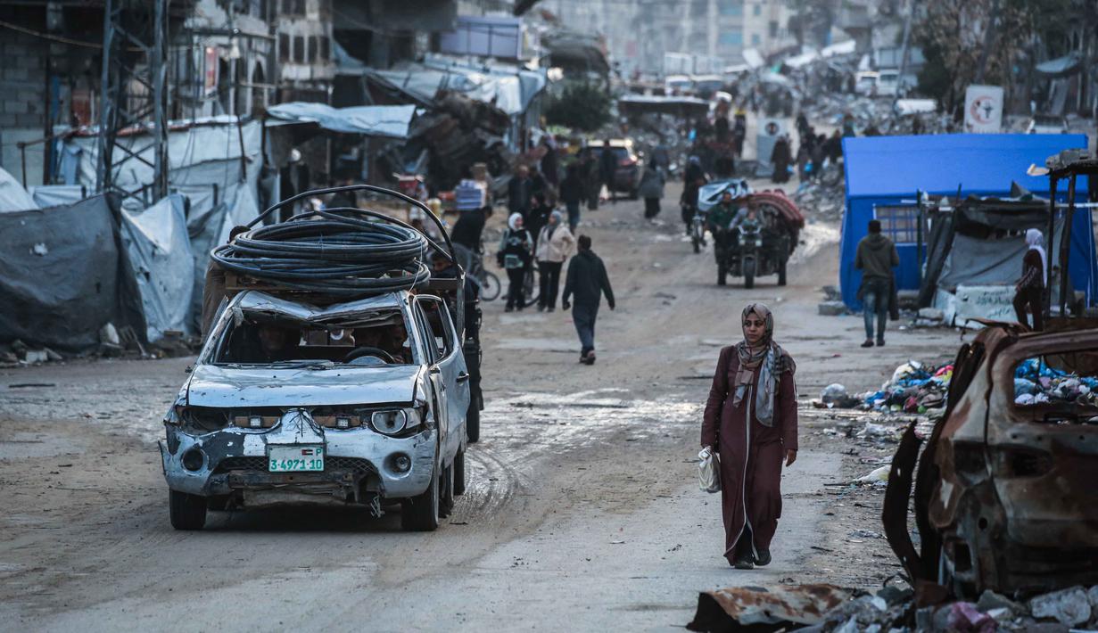 Upaya pemulihan menghadapi tantangan besar karena banyaknya infrastruktur yang luluh lantak akibat serangan Israel dalam dua tahun terakhir. Tampak dalam foto, seorang wanita berjalan di jalan di lingkungan Al-Saftawi, sebelah barat kota Jabalia di Jalur Gaza utara pada Rabu 10 Desember 2025. (BASHAR TALEB/AFP)