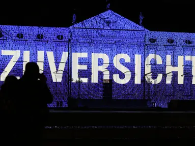 Pengunjung menikmati pemandangan Istana Bellevue yang diterangi proyeksi cahaya bertuliskan "Zuversicht", yang bermakna keyakinan, di Berlin, ibu kota Jerman, pada 17 Desember 2020. Pertunjukan cahaya bertema "Lichtblick" (Seberkas Harapan) ini digelar di Istana Bellevue di Berlin. (Xinhua/Shan Yuqi