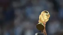 Trofi Piala Dunia FIFA diangkat tinggi-tinggi saat para pemain Argentina merayakan kemenangan mereka atas Prancis di lapangan setelah pertandingan final Piala Dunia Qatar 2022 antara Argentina dan Prancis di Stadion Lusail di Lusail, utara Doha pada 18 Desember 2022. (Paul ELLIS/AFP)