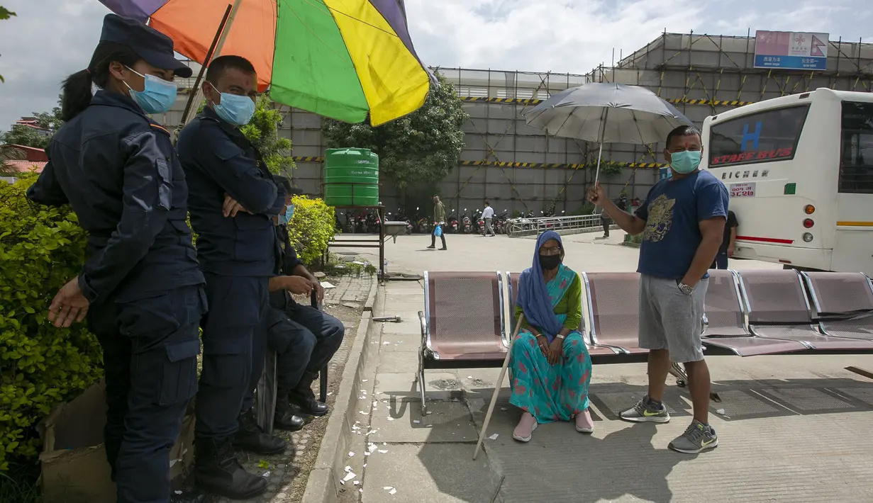 Seorang pria memayungi ibunya yang sudah lansia usai menerima vaksin virus corona COVID-19 AstraZeneca di Kathmandu, Nepal, Senin (9/8/2021). Hingga 8 Agustus 2021, kasus virus corona COVID-19 Nepal mencapai 717.486. (AP Photo/Niranjan Shrestha)
