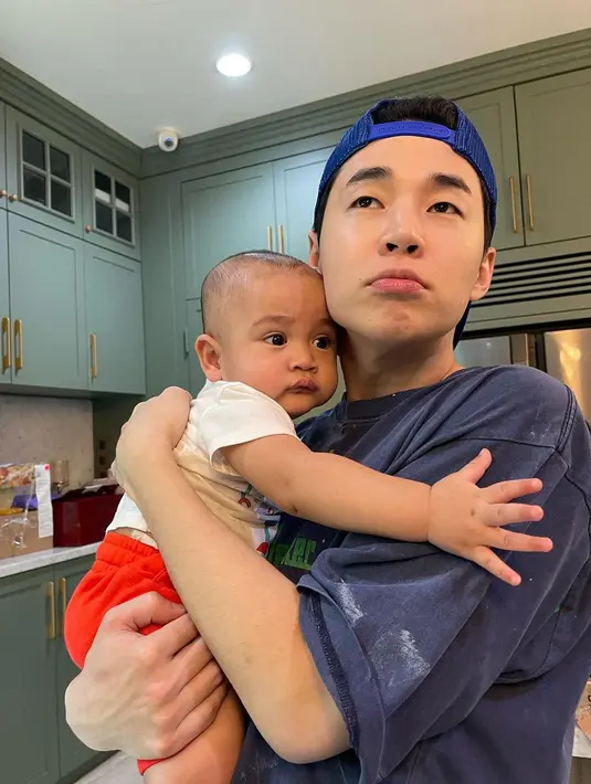 Rayyanza Malik Ahmad tampak anteng digendong oleh Henry Lau. Gemasnya, keduanya memperlihatkan ekspresi wajah yang sama. (Foto: Instagram/ henryl89)