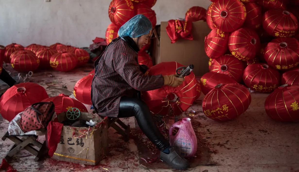 Seorang pekerja sedang membuat lampion merah menjelang perayaan Tahun Baru Imlek di provinsi Hebei, Tingkok (11/1). Jelang perayaan Imlek yang jatuh pada 15 Februari, warga setempat disibukan dengan pembuatan lampion. (AFP Photo/Fred Dufour)