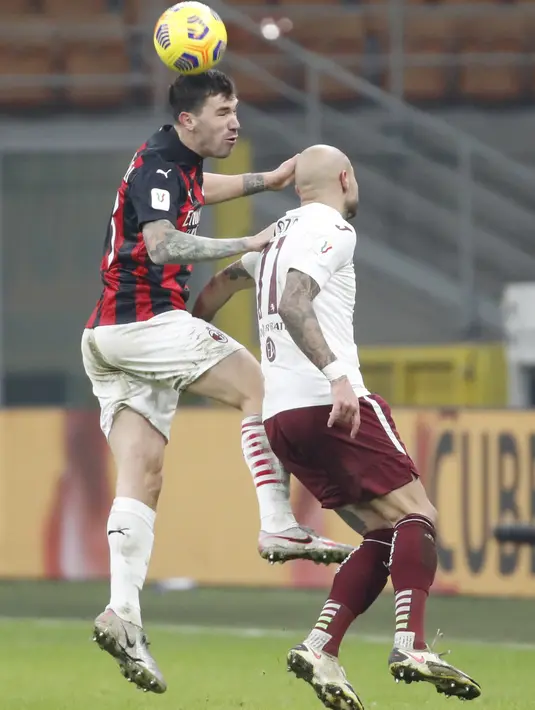 Bek AC Milan, Alessio Romagnoli melompat saat berebut bola dengan penyerang Torino, Simone Zaza pada babak 16 besar Coppa Italia 2020/2021 di San Siro, Rabu (13/1/2021) dini hari WIB. Laga terkunci 0-0, AC Milan menang 5-4 atas Torino di babak adu penalti. (AP Photo/Antonio Calanni)