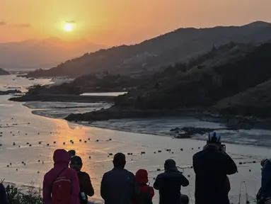 Wisatawan mengambil foto matahari terbenam dari Pulau Dong An di Xiapu, Provinsi Fujian, China, Kamis (12/12/2019). Xiapu menjadi daya tarik tersendiri bagi fotografer pemula karena jauh dari gedung pencakar langit dan hiruk pikuk kota-kota besar di China. (RETAMAL HECTOR/AFP)