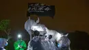 Demonstran antipemerintah mendirikan patung The Lady Liberty of Hong Kong di puncak pegunungan Lion Rock, Hong Kong, Minggu (13/10/2019). Patung tersebut memegang spanduk hitam yang bertuliskan 'Revolusi Zaman Kita, Bebaskan Hong Kong'. (AP Photo/Kin Cheung)