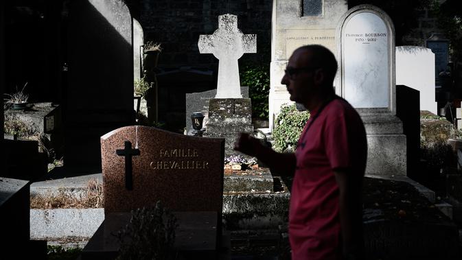 Seorang turis berjalan melewati kuburan di pemakaman Pere Lachaise di Paris (22/7/2019). Pemakaman ini jauh dari kata angker apalagi menyeramkan sebab setiap tahun ribuan bahkan jutaan wisatawan dari berbagai mancanegara berkunjung ke tempat ini. (AFP Photo/Philippe Lopez)