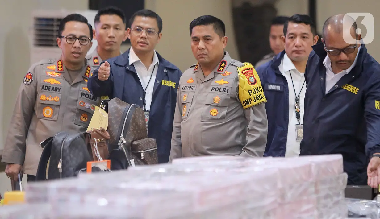 Kapolda Metro Jaya Irjen Karyoto (tengah) mengecek barang bukti yang disita terkait kasus dugaan penyalahgunaan wewenang pemblokiran situs judi online yang melibatkan pegawai Kementerian Komunikasi dan Digital (Komdigi). (Liputan6.com/Herman Zakharia)