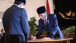 Presiden Joko Widodo menandatangani surat pelantikan Triawan Munaf sebagai Kepala Badan Ekonomi Kreatif di Istana Negara, Jakarta, Senin (26/1/2015). (Liputan6.com/Faizal Fanani)
