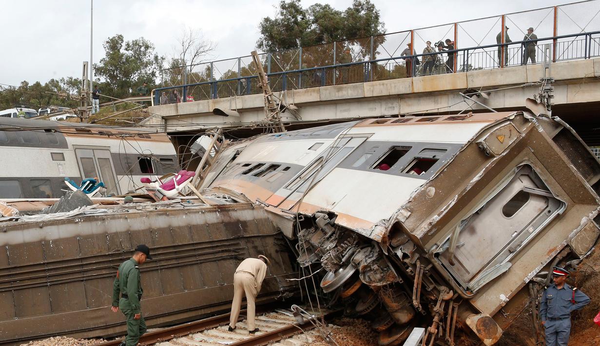 Aparat kepolisian berdiri dekat sebuah kereta api yang terguling di Sidi Bouknadel, Maroko, Selasa (16/10). Kereta yang dalam perjalanan dari Rabat menuju Kenitra telah keluar jalur di sekitar 20 km dekat Sidi Bouknadel. (AP/Abdeljalil Bounhar)